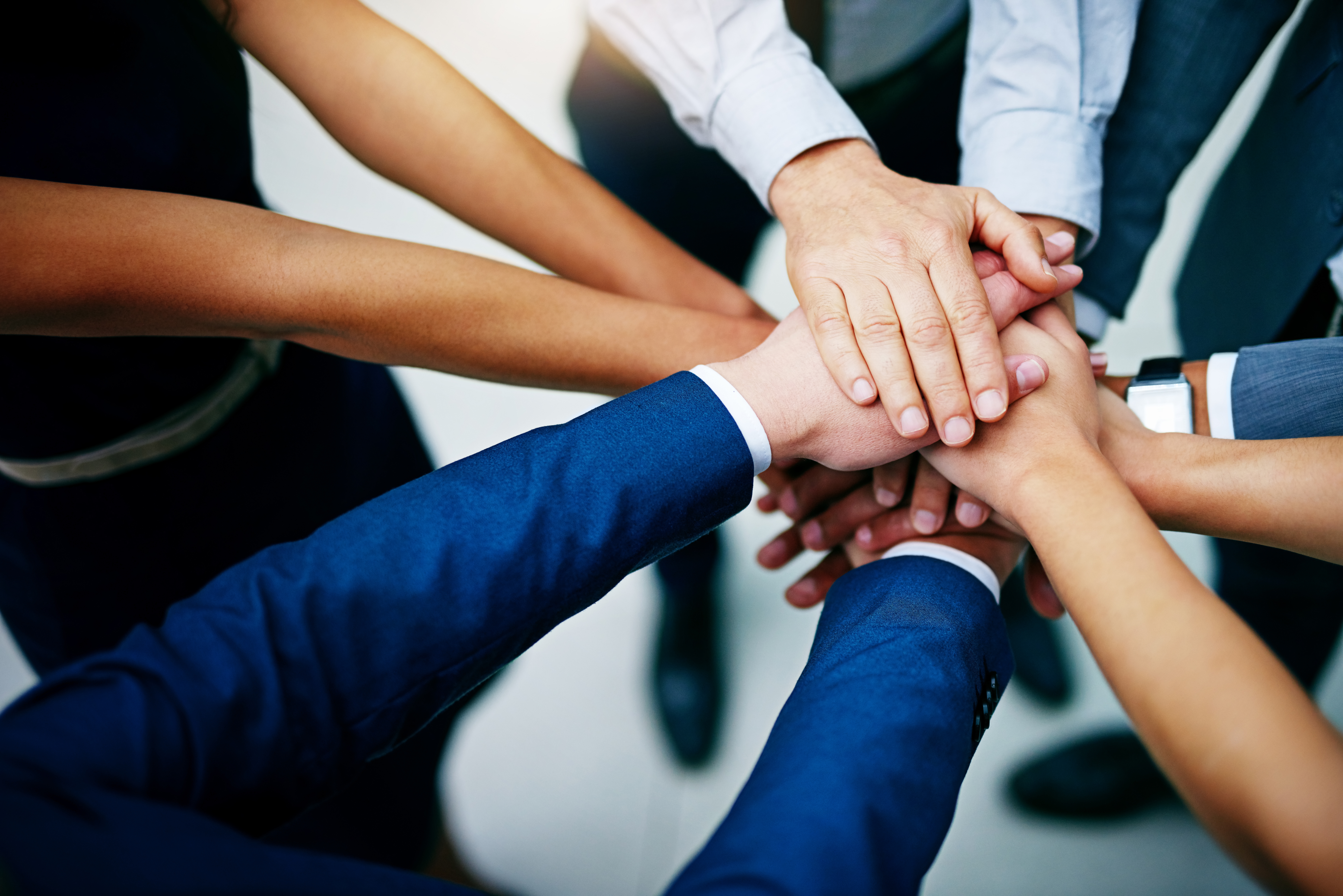Closeup shot of a group of businesspeople joining their hands together in unity