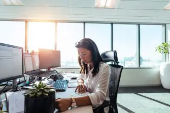 A woman sitting at her desk in front of two computers.